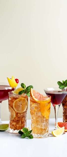 Nosh Lounge Summer alcoholic cocktails: rum cola, long island ice tea, manhattan, cosmopolitan, old fashioned - trendy popular drinks and beverages for cocktail party. Beige background